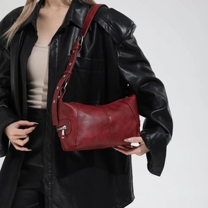 Detail of burgundy leather shoulder bag with silver zipper and metallic eyelet strap