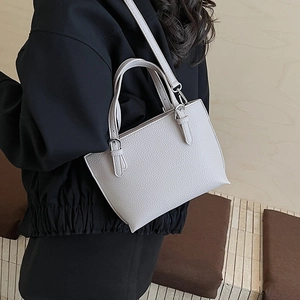 Litchi pattern leather bucket bag shown on shoulder with elegant metal hardware