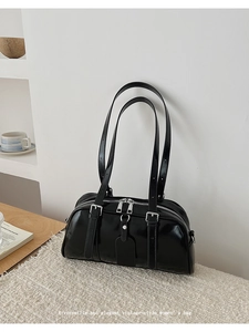 Detail of black glossy patent leather shoulder bag with silver zipper and double straps