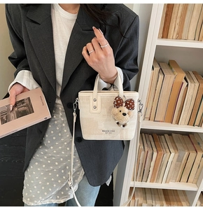 Détail du sac seau en toile beige avec pendentif ours et logo imprimé élégant