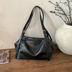 Detail of adjustable silver buckle and vintage leather texture on black tote bag
