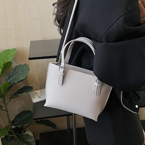 Detail of minimalist beige bucket bag with litchi leather texture and adjustable strap