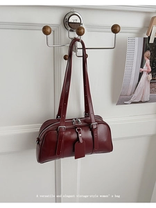 Close-up of deep burgundy leather shoulder bag with adjustable straps and metal zipper