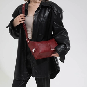 Detail of burgundy leather shoulder bag with silver zipper and metal eyelet wide strap
