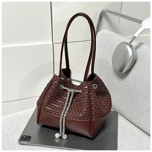 Detail of dark brown woven bucket bag with metal chain drawstring and pearl charms