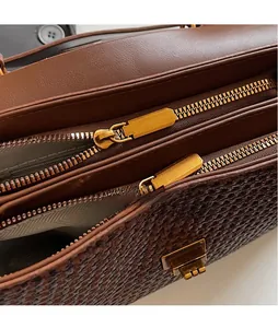 Detail of dual golden zippers and woven texture on a brown retro handbag for women