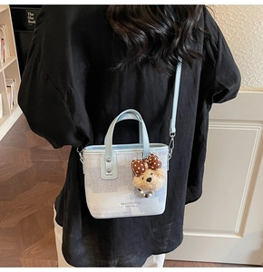 Détail du mini sac cabas en denim bleu clair avec garniture contrastée et charme d'ourson