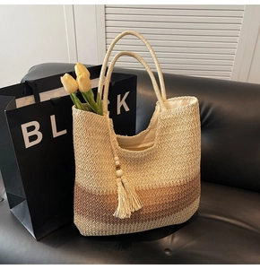 Detail of a gradient straw tote bag with wood bead tassels on a leather background