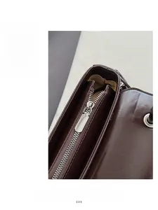 Detailed close-up of dark brown leather handbag with silver metal zipper and fine stitching