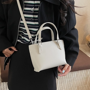 Detail of creamy white leather bucket bag with litchi texture and silver buckle accents