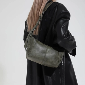 Detail of dark green leather shoulder bag with vintage texture and silver zipper finish