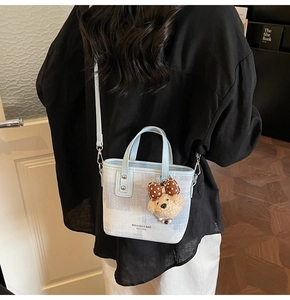 Détail du sac seau à carreaux bleu clair avec un charmant ours en peluche sur la bandoulière