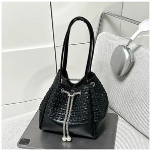 Detail of woven bucket bag with silver chain drawstring and pearl decorative pendants