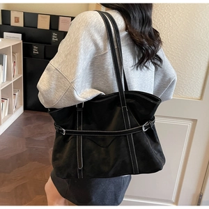 Detail of black leather tote bag featuring white contrast stitching and silver metal buckle