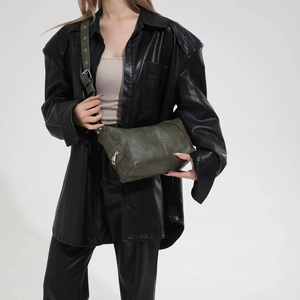 Detail of dark green matte leather crossbody bag with wide strap and metallic eyelets