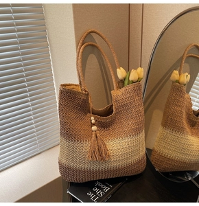 Detail of woven straw tote bag with brown gradient finish and tassel bead charm