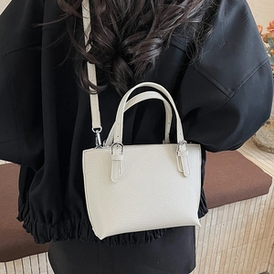 Close-up of white lychee pattern leather bucket bag with silver metal buckles and shoulder strap
