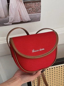 Fashionable red canvas saddle crossbody bag with brown leather trim and hand-held styling