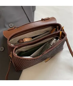 Detail view of woven brown leather handbag interior with multiple functional compartments