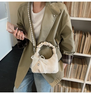 Chic cream dumpling bag with pearl lace details styled in a minimalist lifestyle setting
