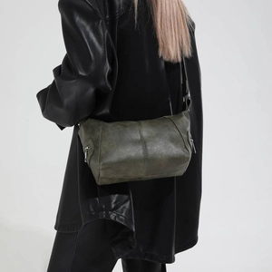 Detail view of vintage dark green shoulder bag with leather stitching and metal zippers
