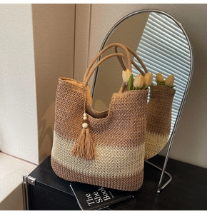 Close-up of woven straw tote bag with tassel pendant and striped pattern detail