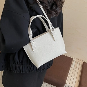 Detail showing the white lychee grain bucket bag on a model with adjustable metal straps