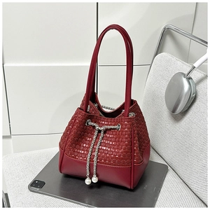Macro shot of dark red woven bucket bag with pearl drawstring and silver chain detail