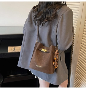 Detailed back view of dark brown suede bucket bag with gold clasp and ethnic beads
