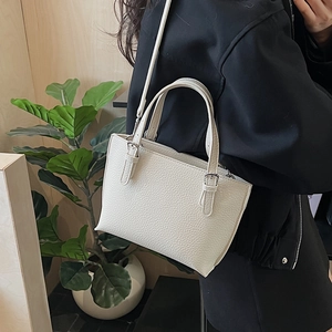 Creamy white bucket bag with pebble leather texture shown in a casual lifestyle setting