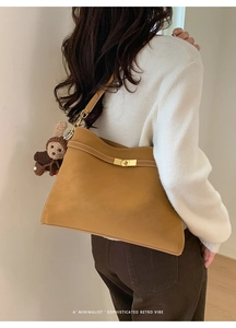Détail d'un sac cabas en cuir marron vintage avec fermoir doré et accessoire peluche