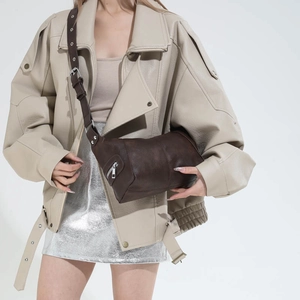 Detail view of brown vintage dumpling bag with silver buckles and a wide shoulder strap