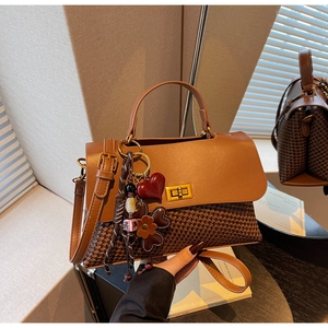 Detail of a brown houndstooth patchwork handbag with gold metal clasp and floral charm
