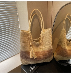 Detailed close-up of a three-color gradient woven straw tote bag with a tassel charm