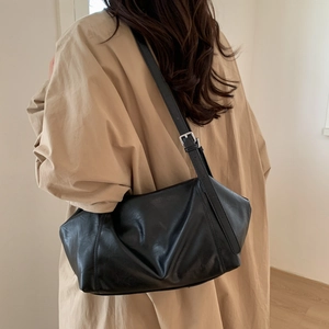 Detail of minimalist black soft leather shoulder bag with adjustable strap and silver buckle