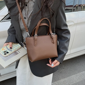 Detailed view of the dark brown lychee leather bucket bag with silver hardware and shoulder strap