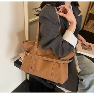 Detailed close-up of brown leather tote bag with silver buckle and fine stitching details