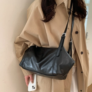 Classic black PU leather tote bag with silver buckle worn by model in beige trench coat