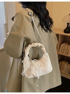 Elegant beige crescent bag with pleated handle, chain strap and pearl bow charm