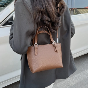 Detail of a brown lychee pattern leather bucket bag shown on model with silver hardware