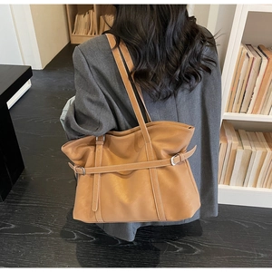 Rear view of a caramel leather tote bag on model showing strap design and large capacity
