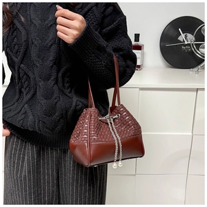 Detailed view of dark brown woven leather bucket bag with elegant pearl drawstring and chain