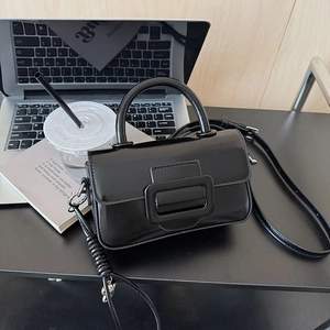 Detail of minimalist black leather square handbag with large square buckle in office setting