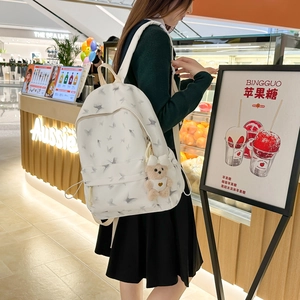 Detailed view of white nylon backpack with butterfly print and plush bear accessory