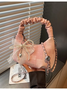 Pink dumpling handbag with lace bow pearl charm and pleated handle on dark background
