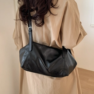 Close-up of black leather tote bag with adjustable strap and silver buckle hardware