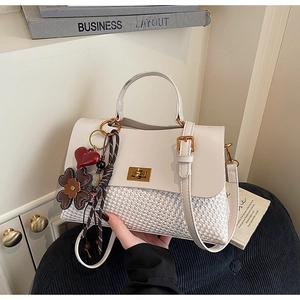 Detail of beige tote bag with golden twist lock and colorful fashion charms