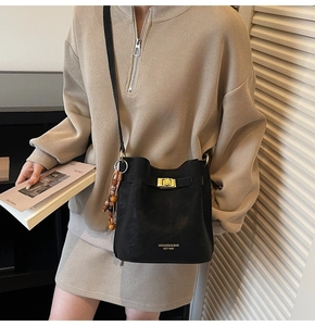 Detail of black matte leather bucket bag with gold twist lock and bead charm