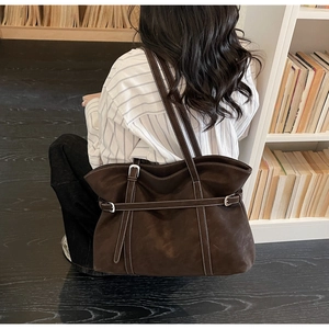 Detail of vintage brown suede tote bag with contrast stitching and decorative buckle strap
