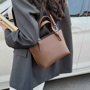 Street style shot of a brown bucket bag worn crossbody with a grey suit for commuting